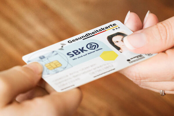 Eine Person übergibt ihre SBK-Gesundheitskarte an eine andere Person.