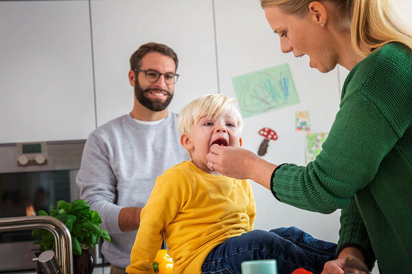 Eine Mutter lässt ihren Sohn beim Kochen vom Essen probieren.