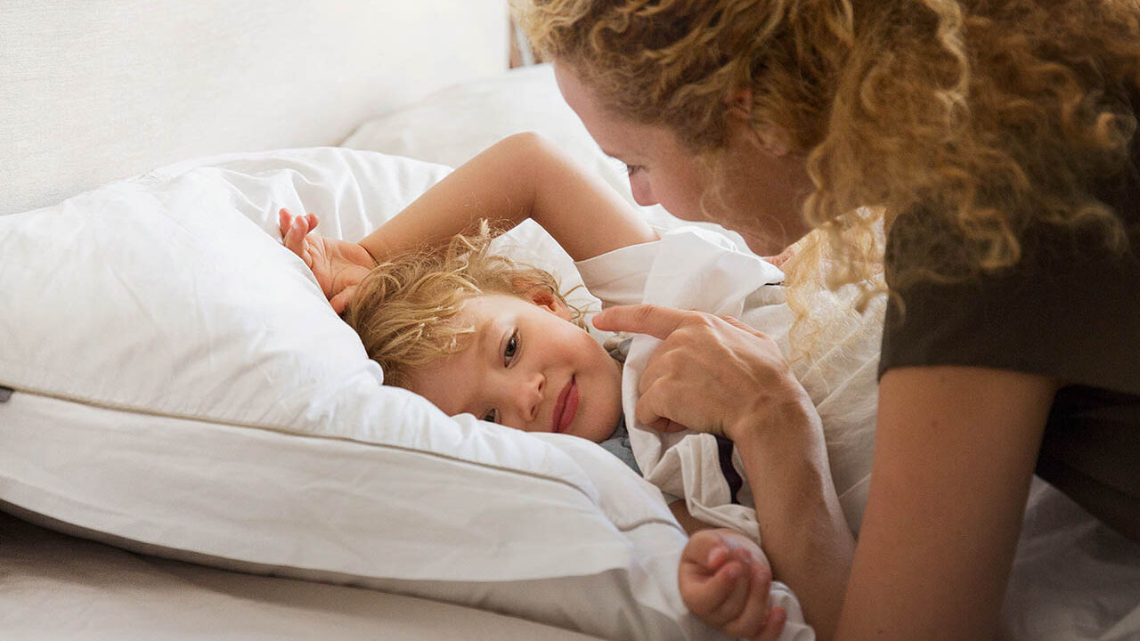 Eine Mutter weckt morgens ihren Sohn liebevoll.