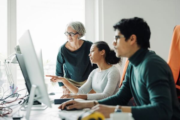 Drei Menschen arbeiten gemeinsam an einem Monitor