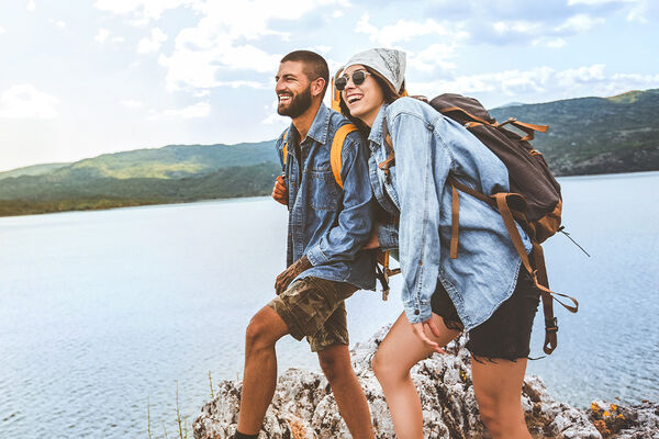 Wanderer mit Rucksäcken auf Klippe genießen am Bergsee