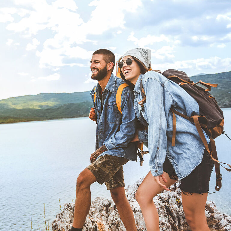 Wanderer mit Rucksäcken auf Klippe genießen am Bergsee