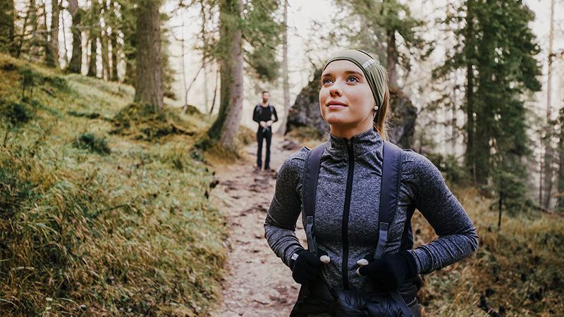 Frau genießt Wandern im Wald und ein Mann im Hintergrund