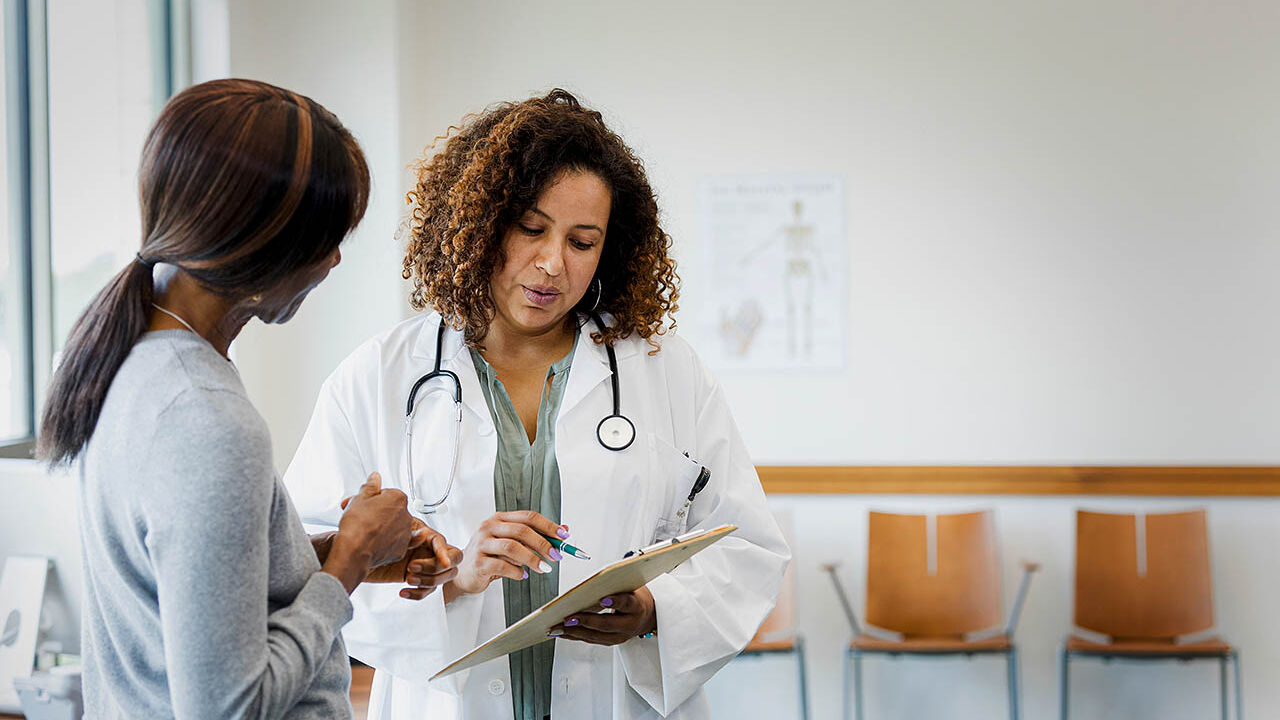 Eine Ärztin erklärt einer Frau die Untersuchungsergebnisse auf einem Dokument.