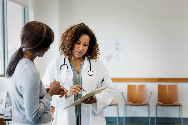 Eine Ärztin erklärt einer Frau die Untersuchungsergebnisse auf einem Dokument.