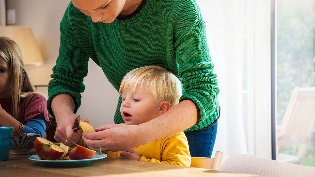Eine Mutter schneidet einen frischen Apfel für ihren Sohn auf.
