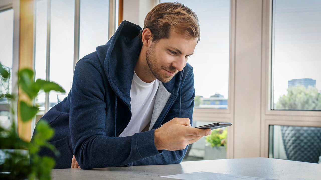 Ein Mann macht mit seinem Handy ein Foto eines Dokuments.