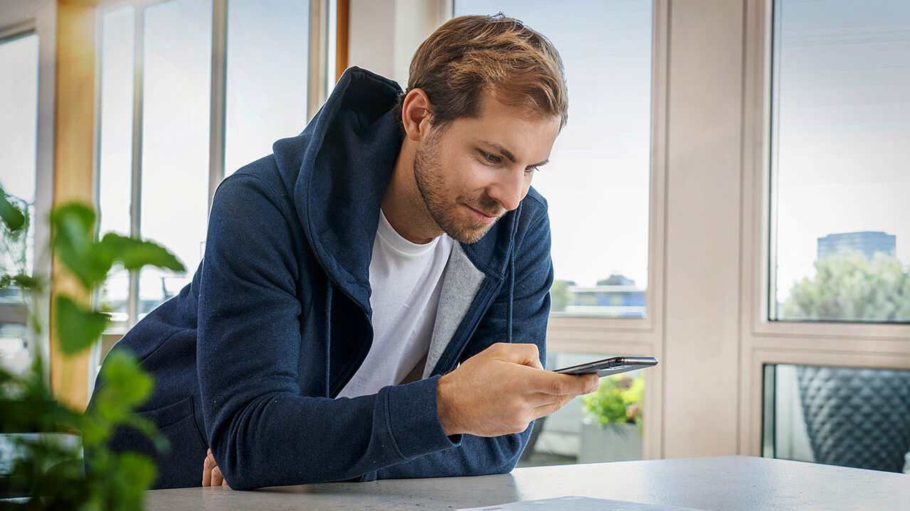 Ein Mann macht mit seinem Handy ein Foto eines Dokuments.