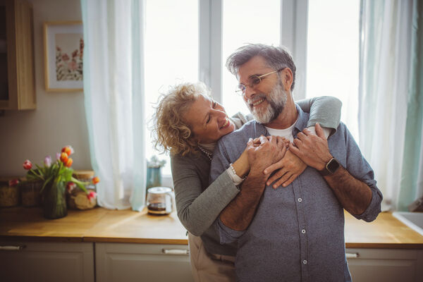 Ein älteres Paar umarmt sich glücklich in der Küche.