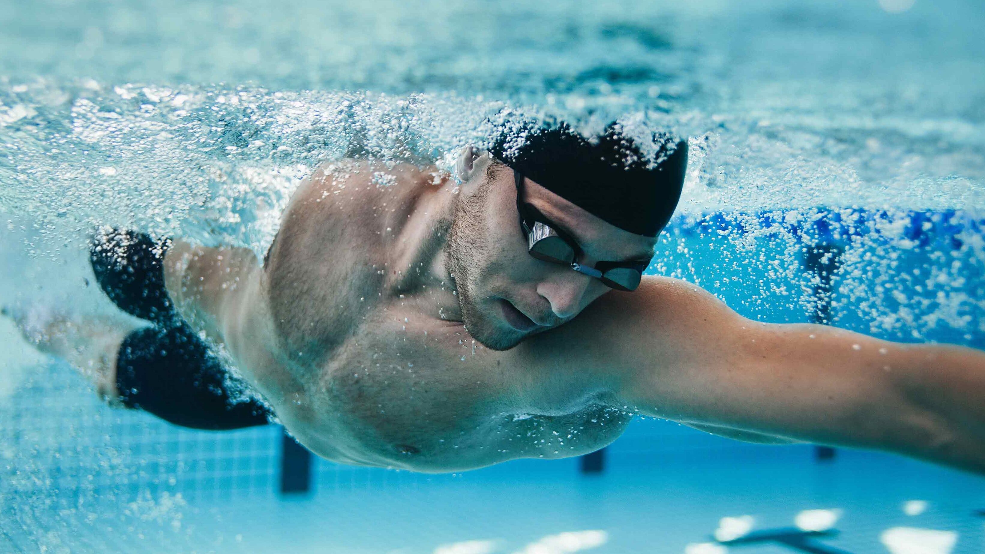 Mann mit Schwimmbrille unterwasser im Sportbecken