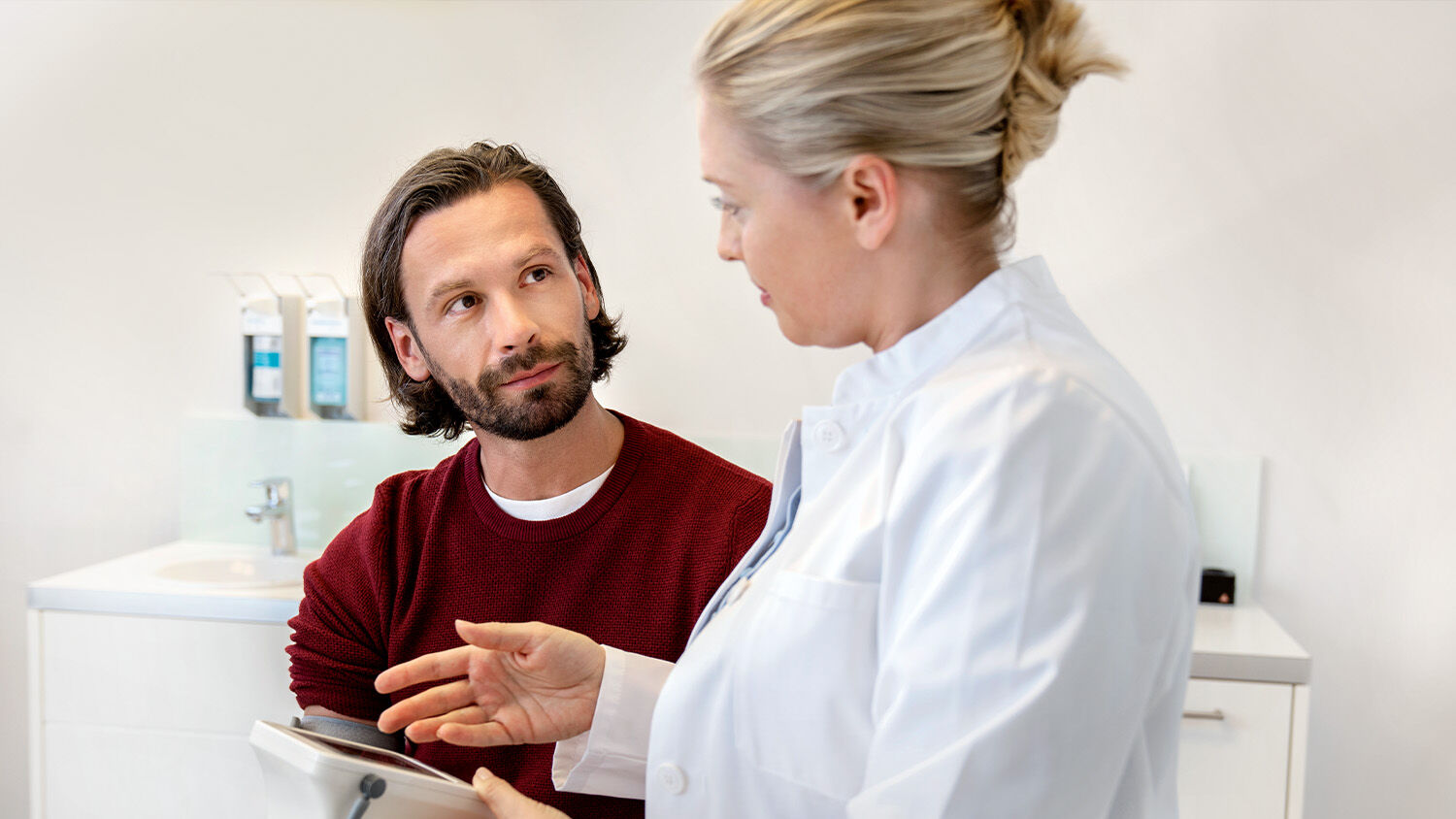 Mann  im Gespräch mit Ärtzin, Blutdruckmessung