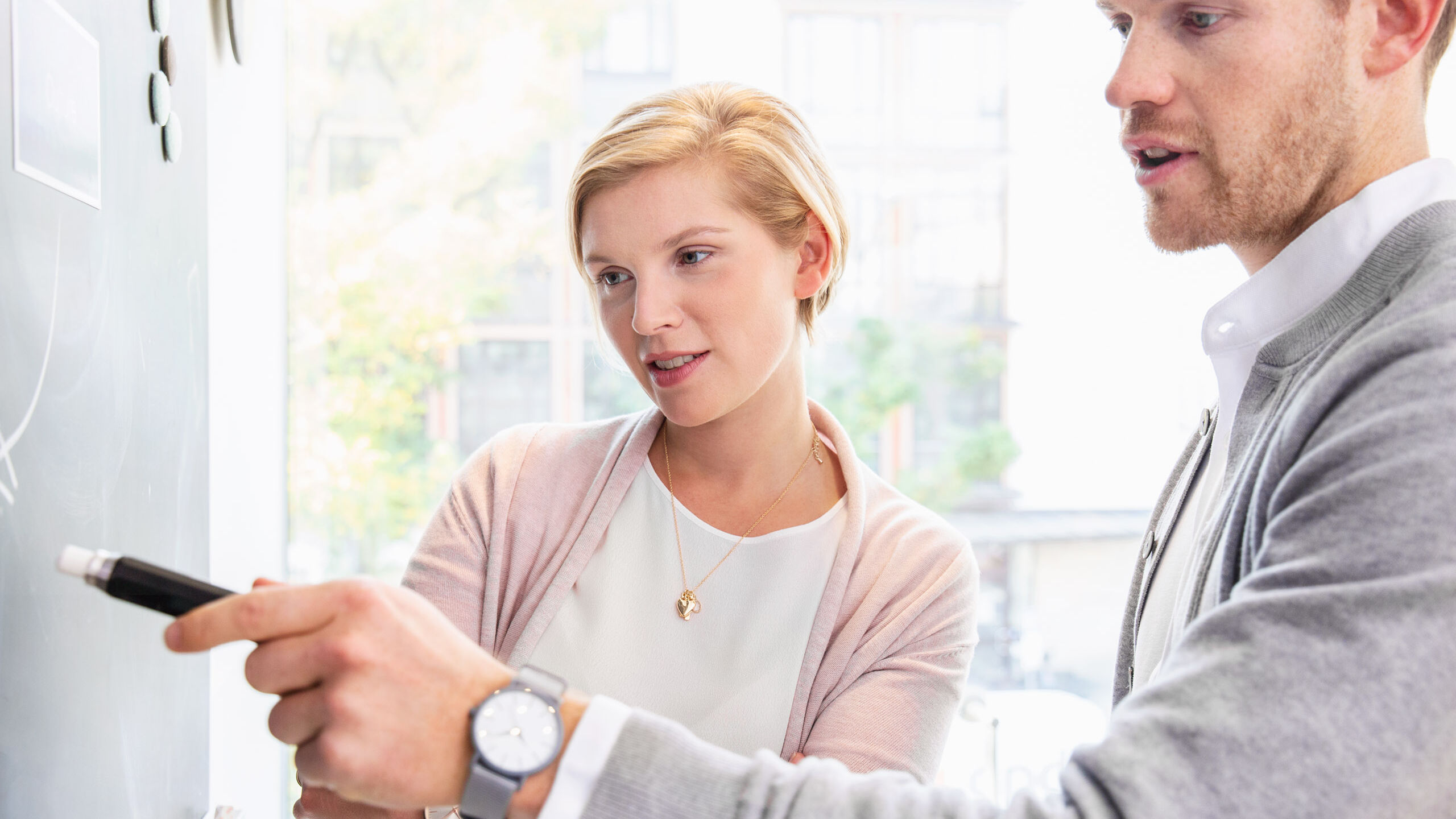 Zwei Menschen schauen auf eine Tafel und sprechen miteinander