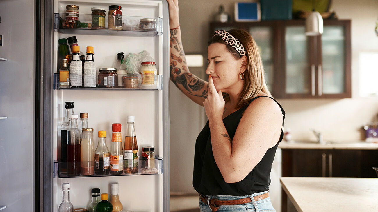 Eine Frau steht vor einem offenen Kühlschrank