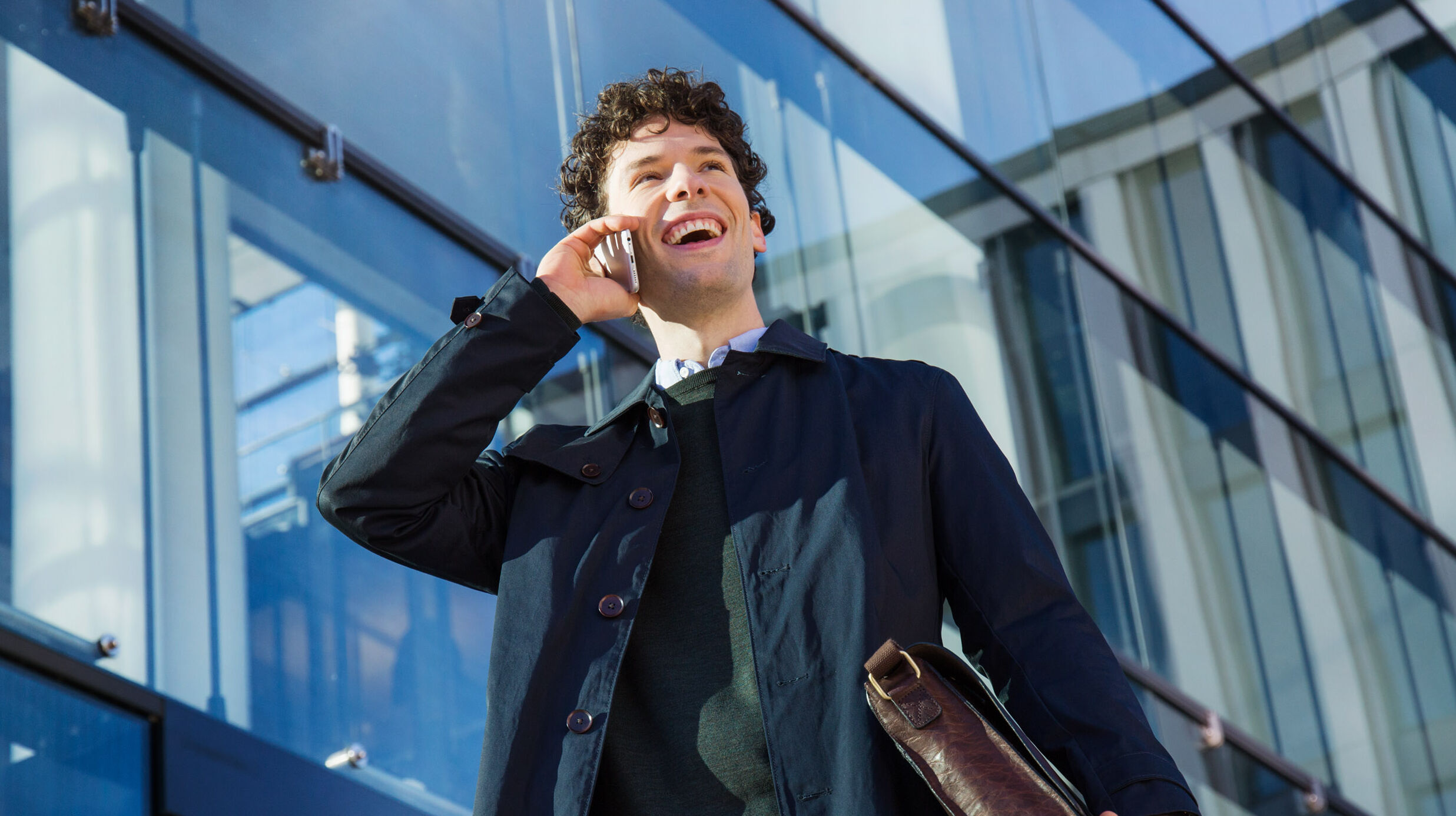Junger Mann telefoniert vor Glaswand