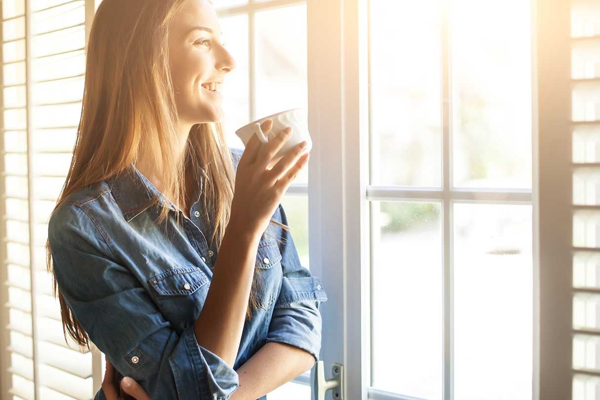 Frau steht am Fenster 