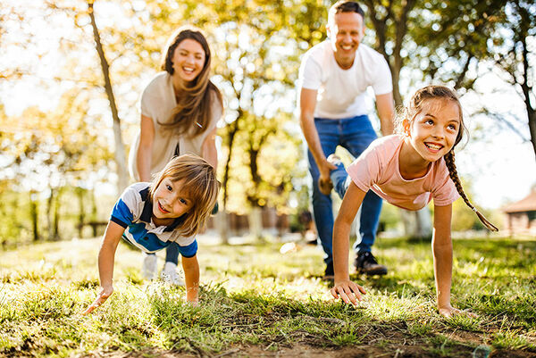 Kinder, die mit ihren Eltern bei einem Schubkarrenrennen in der Natur Spaß haben