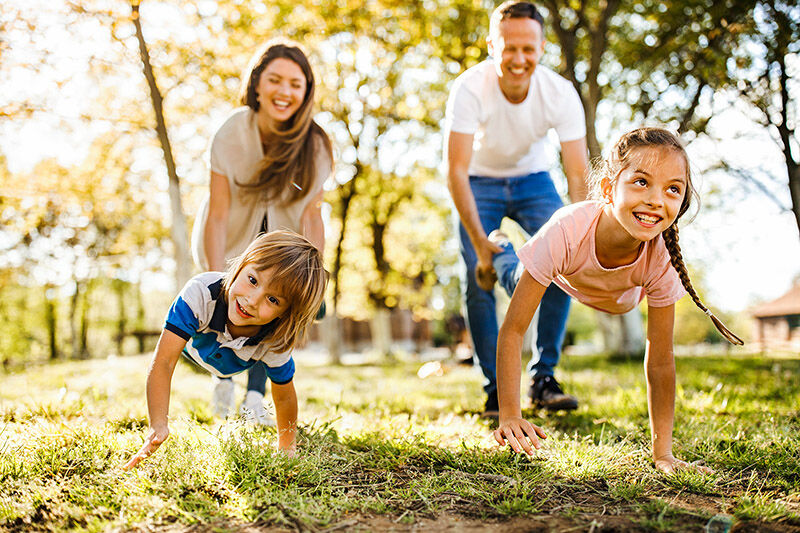 Kinder, die mit ihren Eltern bei einem Schubkarrenrennen in der Natur Spaß haben