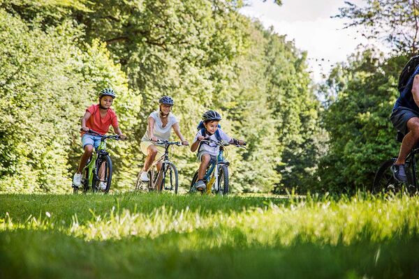 Eine Familie ist an einem sonnigen Sommertag mit dem Fahrrad in der Natur unterwegs.