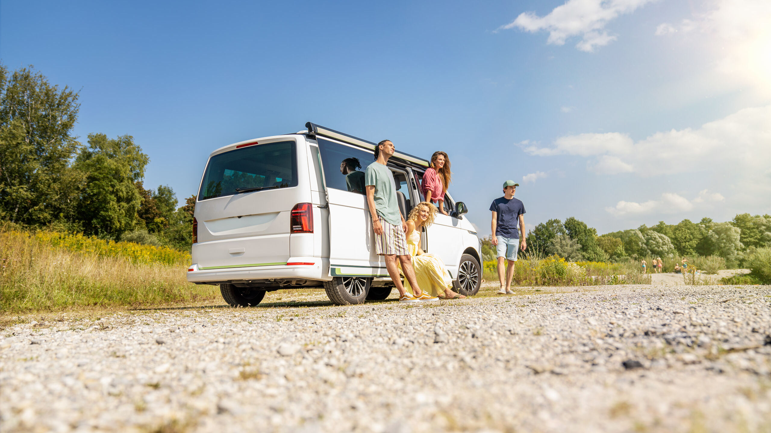 Vier Jugendliche stehen neben einem Camping-Bus.