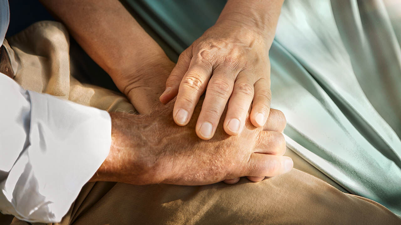 Ein älteres Paar hält sich gegenseitig die Hände.