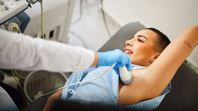 Eine Frau wird mit einem Ultraschallgerät an der Brust untersucht.