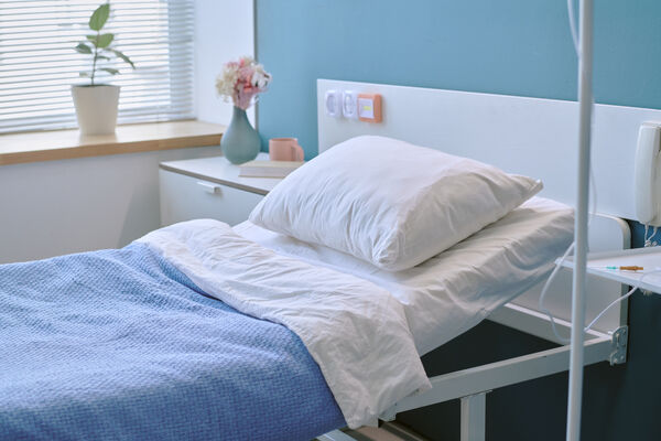 Ein leeres Pflegebett in einem lichtdurchfluteten Raum am Fenster