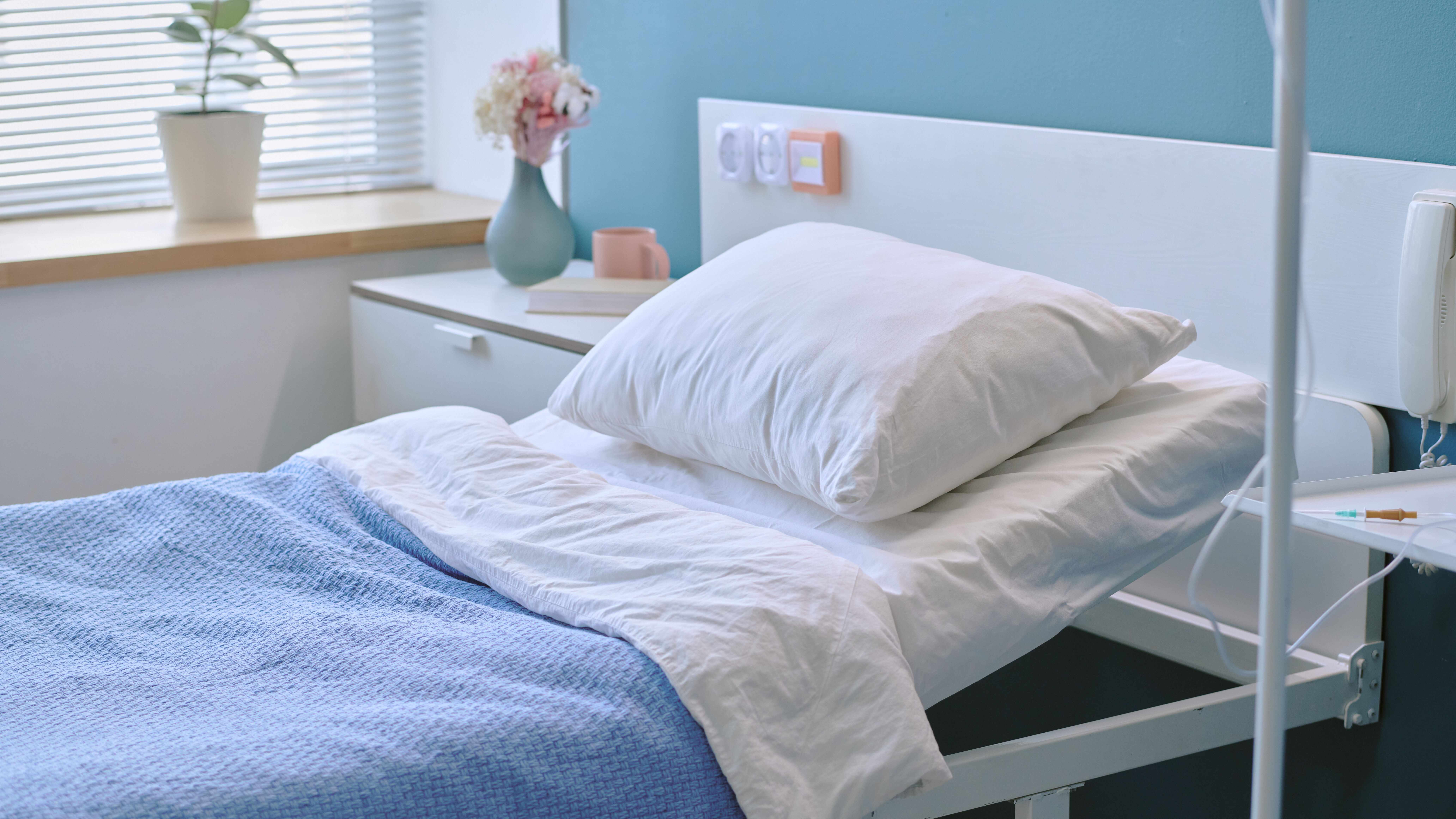 Leeres Pflegebett in lichtdurchflutetem Raum am Fenster