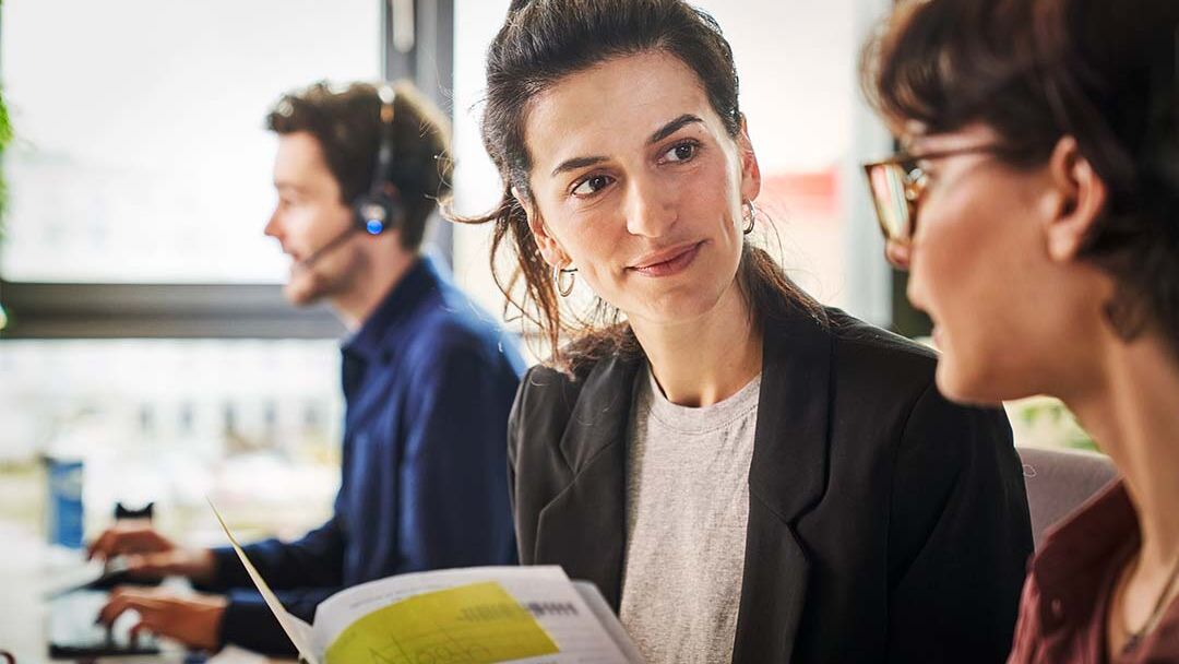 Am Arbeitsplatz sprechen zwei Frauen über ein Dokument