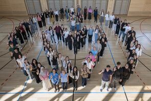Auszubildende stehen in Herzform in einer Turnhalle