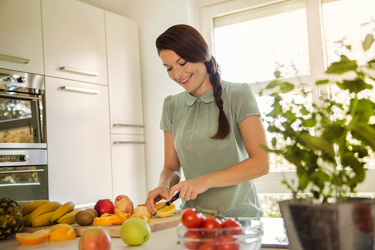 Eine Frau schneidet frisches Obst in einer Küche.