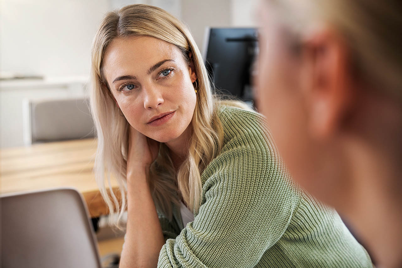 Eine Frau unterhält sich gerade mit einer anderen Frau, ihr Blick ist interessiert.. 