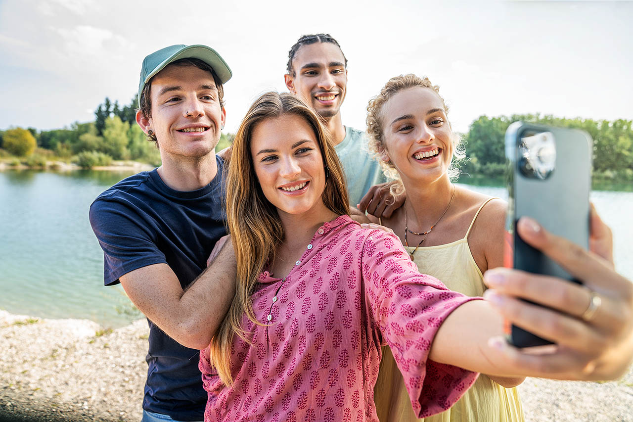 Eine Gruppe junger Erwachsener macht gemeinsam ein Selfie vor einem See.