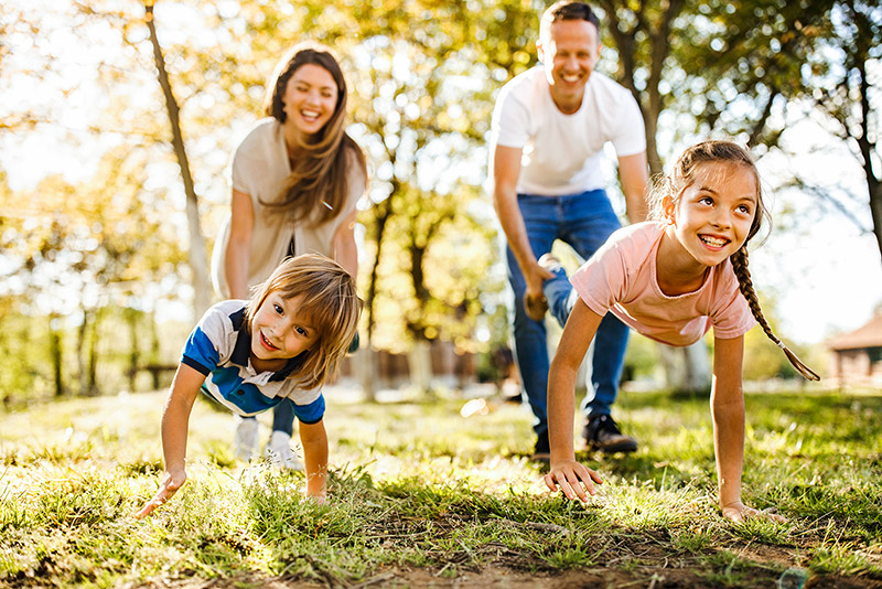 Kinder, die mit ihren Eltern bei einem Schubkarrenrennen in der Natur Spaß haben