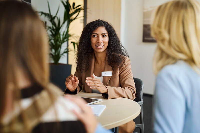 Eine Mitarbeiterin der SBK sitzt mit einer Kundin und ihrer Tochter an einem Tisch und berät sie.