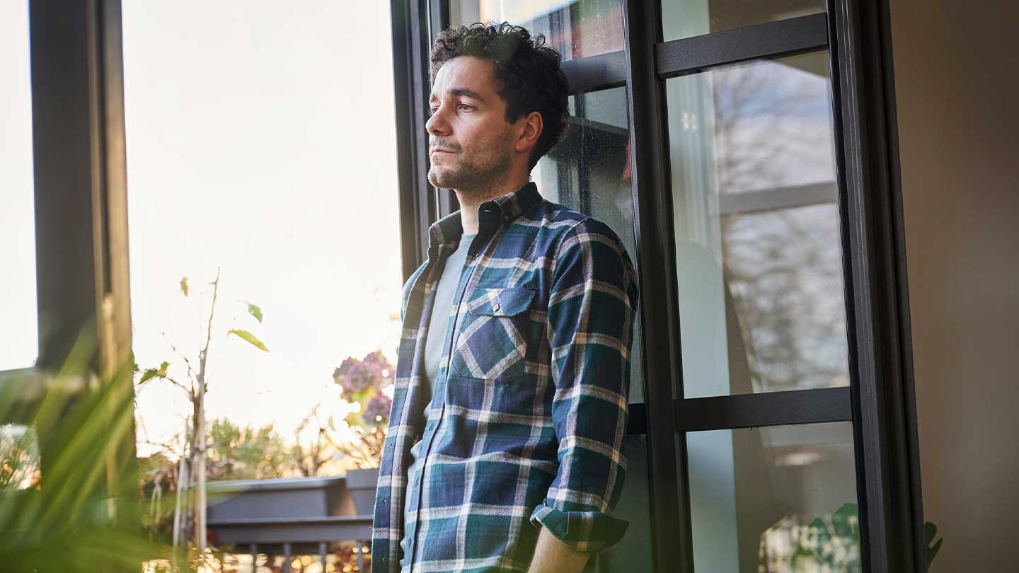 Mann steht vor Fenster.