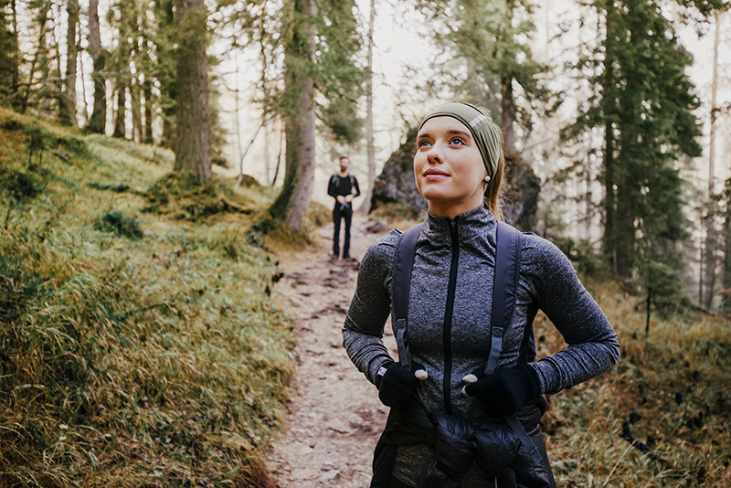 Frau genießt Wandern im Wald und ein Mann im Hintergrund