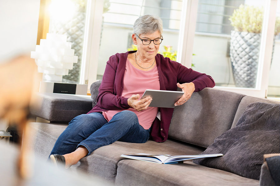 Frau mit Tablet auf Sofa.
