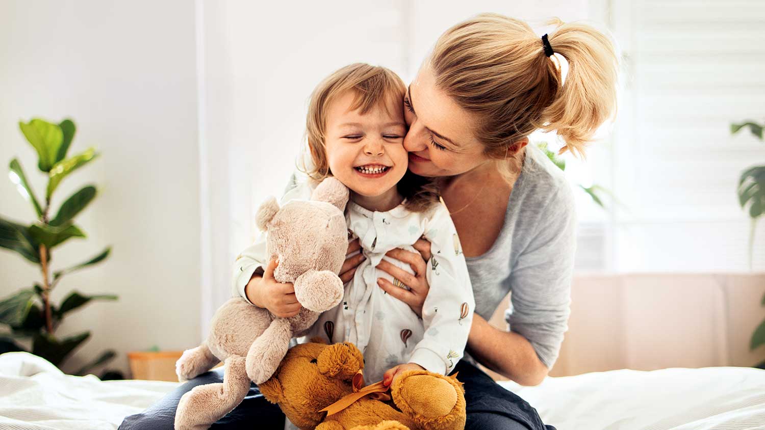Eine blonde Frau sitzt mit ihrem Kind auf dem Bett