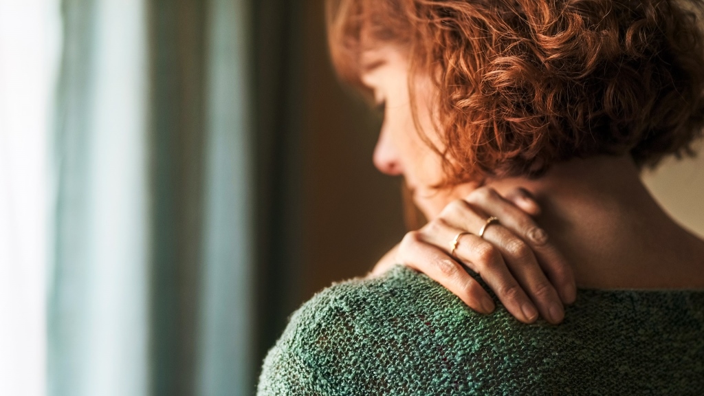 Rückansicht einer Frau, die an Schulterschmerzen leidet