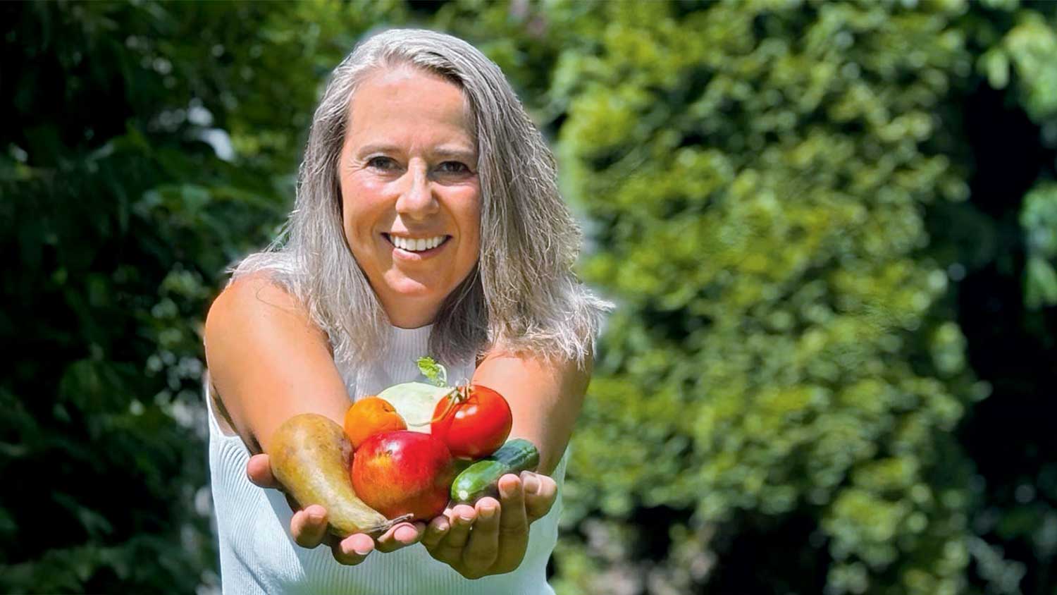 Frau hält Gemüse in der Hand.